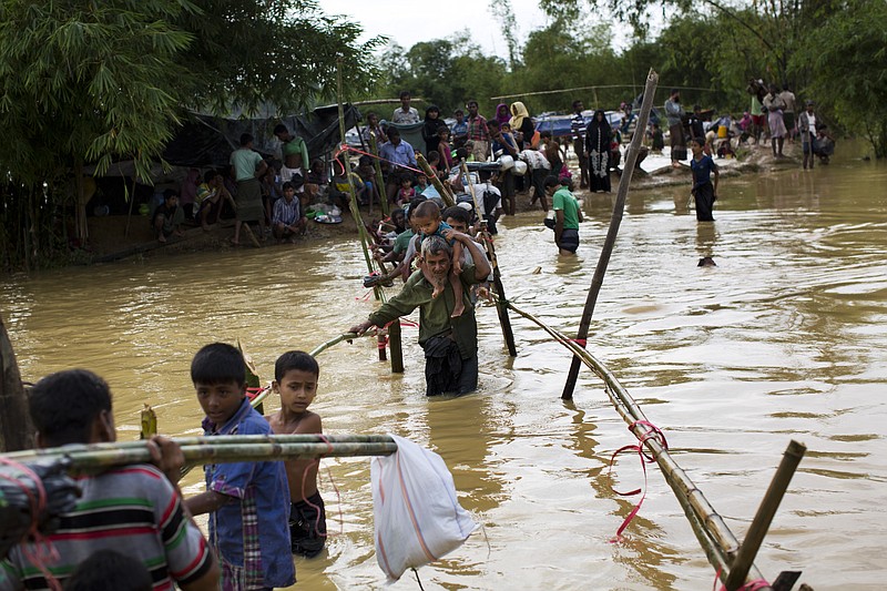 Rohingya Muslims, who crossed over recently from Myanmar into Bangladesh, cross a flooded area to find alternate shelter after their camp was inundated with rainwater near Balukhali refugee camp, Bangladesh, Tuesday, Sept. 19, 2017. With a mass exodus of Rohingya Muslims sparking accusations of ethnic cleansing from the United Nations and others, Myanmar leader Aung San Suu Kyi on Tuesday said her country does not fear international scrutiny and invited diplomats to see some areas for themselves. (AP Photo/Bernat Armangue)