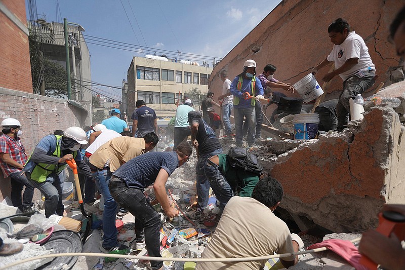 Rescue workers and volunteers search for survivors at the Ninos Heroes neighborhood in Mexico City, Tuesday Sept. 19, 2017. A magnitude 7.1 earthquake has stunned central Mexico, killing more than 100 people as buildings collapsed in plumes of dust.