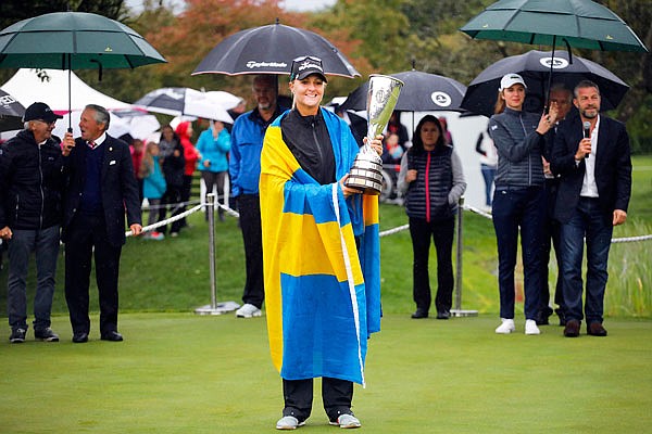 As officials huddle under umbrellas, Anna Nordqvist celebrates with her trophy after winning the Evian Championship last Sunday in Evian, France.