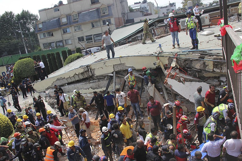 Rescue workers search Tuesday, Sept. 19, 2017, for children trapped inside the collapsed Enrique Rebsamen school in Mexico City. The earthquake stunned central Mexico, killing more than 100 people as buildings collapsed in plumes of dust.