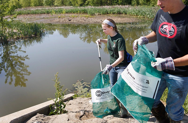 In this May 17, 2014 photo, Kimberlyn Eversman (left) collects trash with Cole Stackman along the banks of Binder Lake.