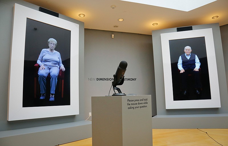 In this Friday Sept. 15, 2017 photo, Holocaust survivors Eva Schloss, left, Anne Frank's posthumous stepsister when her mother married Frank's father, and fellow survivor Pinchas Gutter are displayed as part of an exhibit at the Museum of Jewish Heritage called "New Dimensions in Testimony" in New York City. Visitors can ask them questions which are answered based on hours of recorded interviews.