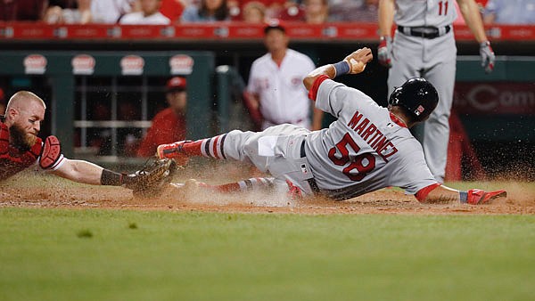 Jose Martinez of the Cardinals scores on a double by Yadier Molina as Reds catcher Tucker Barnhart tries to apply a tag during the seventh inning of Thursday night's game in Cincinnati.