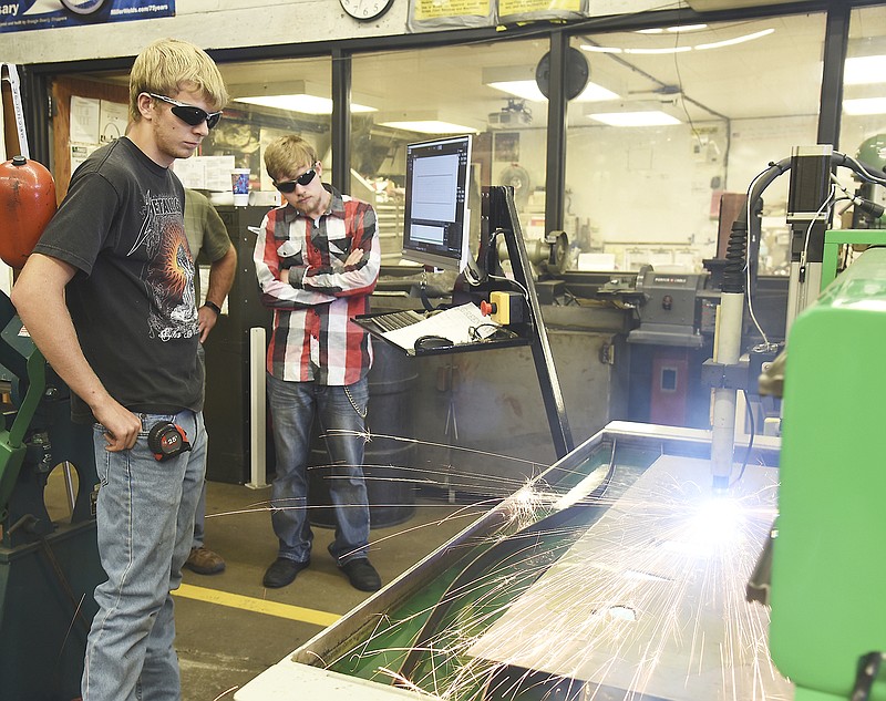 Brandon Wells, left, and Colton Conway watch as the plasma cutter makes lettering cutouts from a solid sheet of metal. Both are seniors at New Bloomfield High School and attend Nichols Career Center.