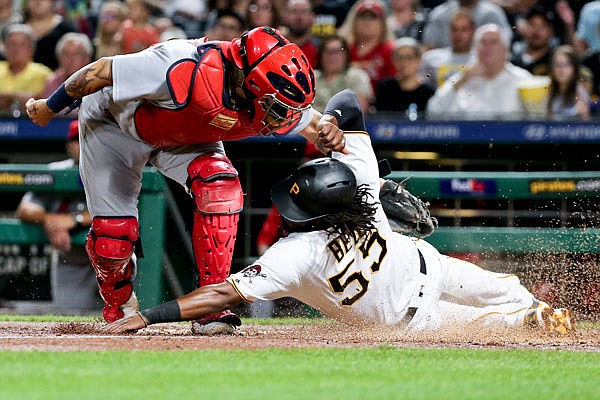 Josh Bell of the Pirates slides under a tag by Cardinals catcher Yadier Molina during the fourth inning of Friday night's game in Pittsburgh.