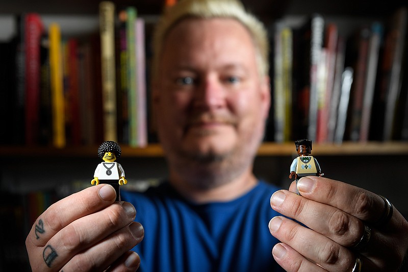 Roy Cook holds two Lego figurines, which he says "show the complex representations of blackness in Lego." The Lego on the left shows a "black skin tone in a world where their (skin tones) are all the same," he said on September 14, 2017, at the University of Minnesota. 