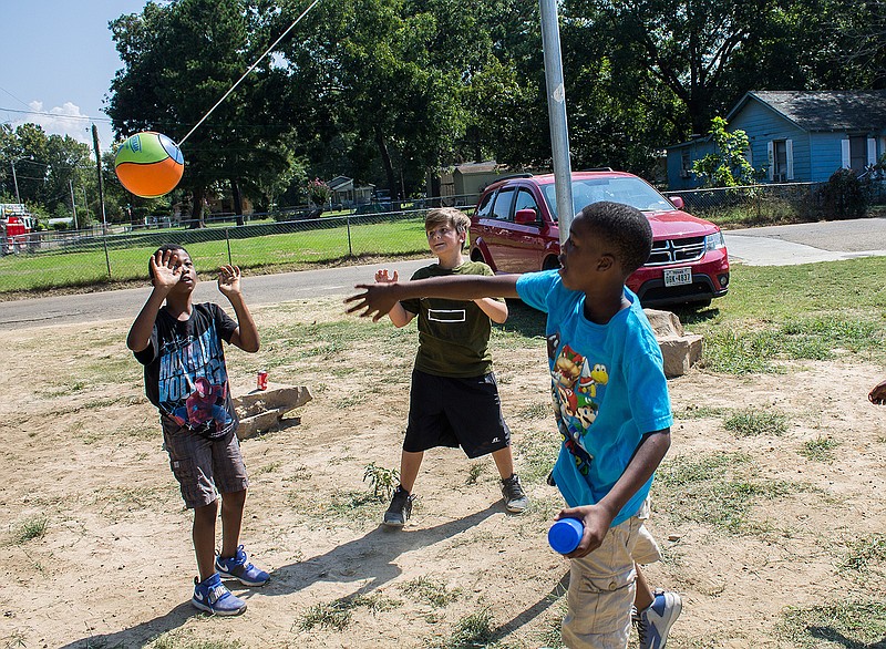 Landon Sims, Kaden Daniel Walker and Kerwin Hooper play tetherball Saturday at the Alpha Park grand opening block party in Texarkana, Ark.