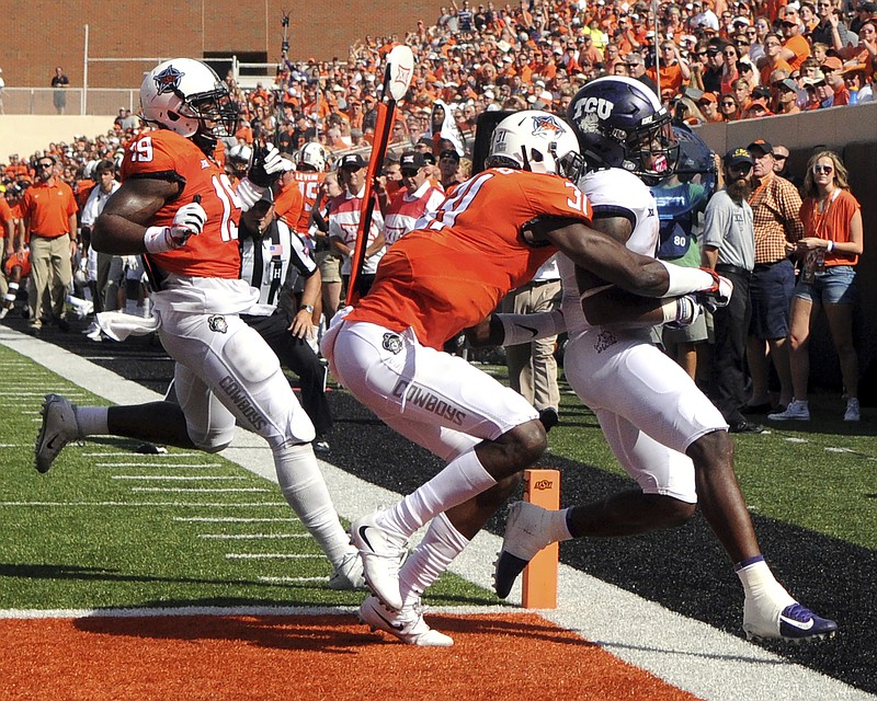 TCU running back Darius Anderson (6) scores a touchdown under pressure from Oklahoma St safety Tre Flowers (31) and linebacker Justin Phillips (19), during the first half of an NCAA college football game in Stillwater, Okla., Saturday, Sept. 23, 2017.