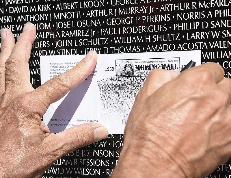 In this September 2015 file photo, a visitor to the Vietnam Moving Wall locates the name of a service member with whom they served in order to etch it onto the paper provided.