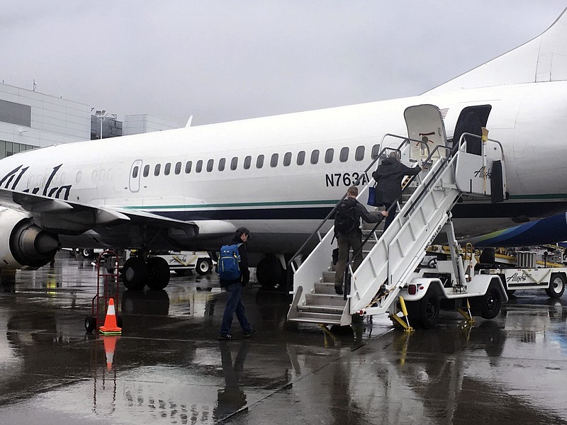 In this photo taken Friday, Sept. 22, 2017, passengers board an Alaska Airlines jet from the rear using stairs at Ted Stevens Anchorage International Airport in Anchorage, Alaska. The airline is retiring its combi planes, Boeing 737-400s designed to be half cargo immediately behind the cockpit and then seating for 72 passengers in the rear. (AP Photo/Mark Thiessen)