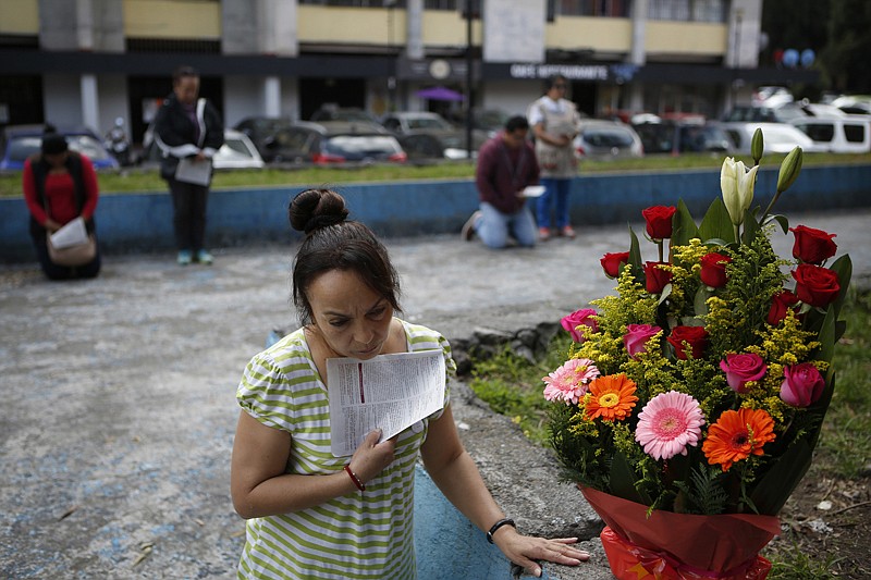 People kneel in prayer Sunday during a Mass service held outside Saint James Apostle Parish because the church building suffered some damage during the 7.1-magnitude earthquake in the Plaza de las Tres Culturas in Tlatelolco, Mexico City.