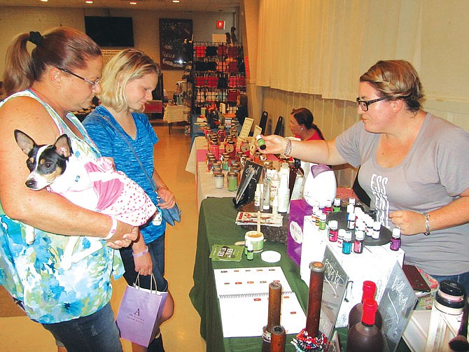 From left, Julie and Britney Hentges shop with their dog, Baeler, on Sunday at the fourth annual Pairings for Pets, sponsored by People Helping Paws. At right is Amy Hodges, owner of Fleurish Oils. 