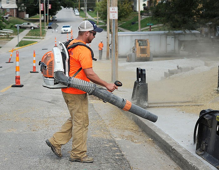 Isaiah Albertson of Concrete Solutions cleans off a new sidewalk off the 900th block of Broadway in Jefferson City on Monday. The concrete is done being poured and construction is close to completion. 