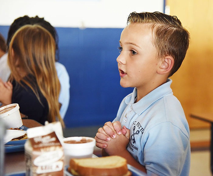 Landon Connally prays before lunch at St. Peter School, where the kindergartener is trying to collect enough food to fill his family's minivan for a food drive.