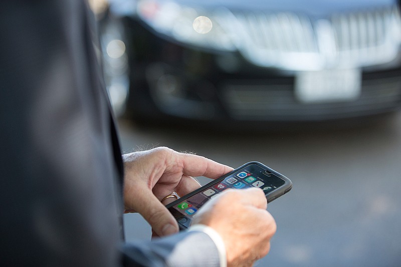 Texas House Rep. Gary VanDeaver uses his phone Tuesday to take the ceremonial first Uber ride in Texarkana, Texas.