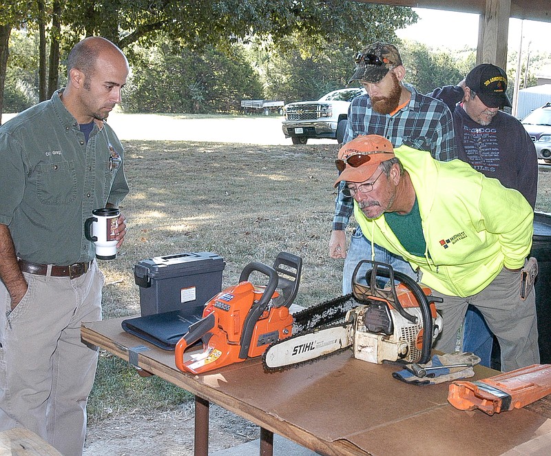 <p>Cory Gregg, resource forester with the Missouri Department of Conservation, left, and frequent chainsaw user Jim Sommerer check out a couple of chainsaws for maintenance and safety features.</p>