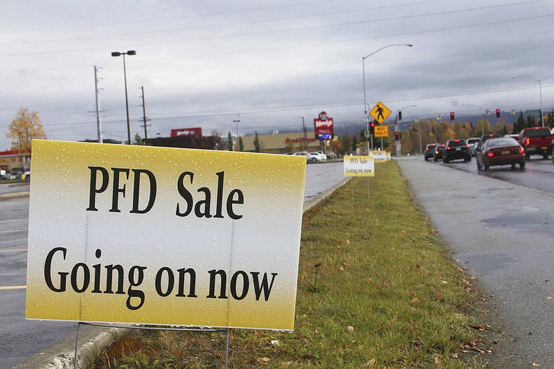 A sign meant to entice recipients of payouts from the state's Permanent Fund Dividend Division, also known as PFD, advertises a sale in Anchorage, Alaska, Wednesday, Oct. 4, 2017. Nearly every Alaskan will wake up $1,100 richer on Thursday, thanks to this year's payout from the state's oil wealth investment fund. The distribution from the Alaska Permanent Fund is essentially free money for residents, who already don't pay a state income tax or statewide sales tax. (AP Photo/Mark Thiessen)