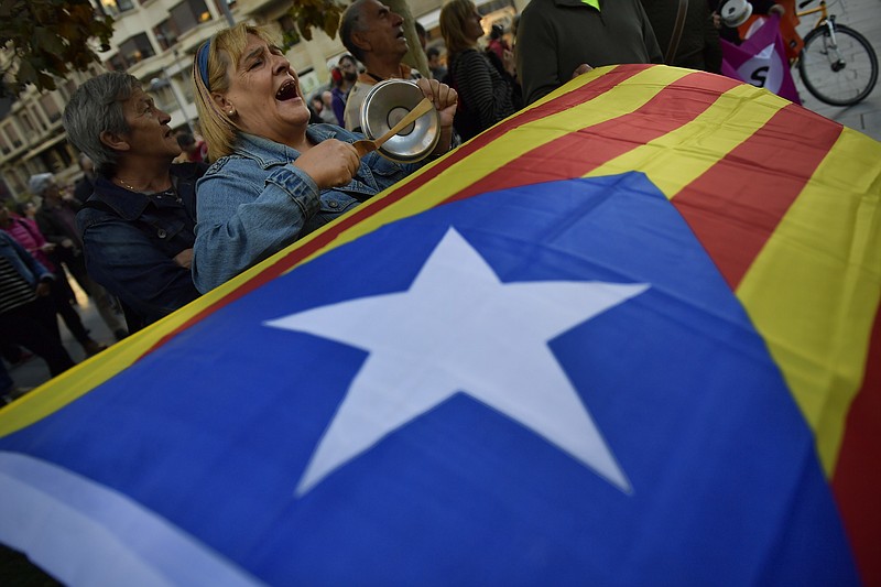 Pro-independence supporters shout slogans in front of the Popular Party headquarters as a "esteleda" or  pro-independence flag is held up, in support of the Catalonia's secession, in Pamplona, northern Spain, Friday, Oct. 6, 2017. (AP Photo/Alvaro Barrientos)