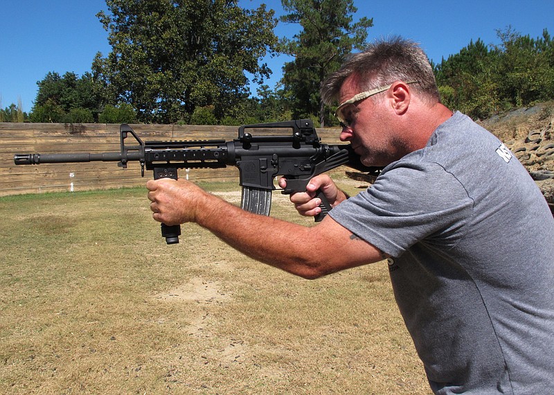 Shooting instructor Frankie McRae aims an AR-15 rifle fitted with a "bump stock" at his 37 PSR Gun Club in Bunnlevel, N.C., on Wednesday, Oct. 4, 2017. The stock uses the recoil of the semiautomatic rifle to let the finger "bump" the trigger, making it different from a fully automatic machine gun, which are illegal for most civilians to own. (AP Photo/Allen G. Breed)