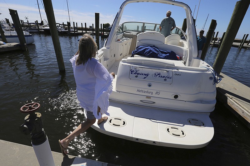 Brenda Kent jumps on her boat as she and her husband leave the Biloxi Small Craft Harbor in Biloxi, Miss., on Friday, Oct. 6, 2017 to take the boat up river in advance of Tropical Storm Nate.  Gulf Coast residents were bracing Friday for a fast-moving blast of wind, heavy rain and rising water as Tropical Storm Nate threatened to reach hurricane strength before a weekend landfall.   (John Fitzhugh/The Sun Herald via AP)