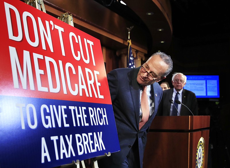 Senate Minority Leader Chuck Schumer of New York, followed by Sen. Bernie Sanders, I-Vt., look at a poster at the start of a news conference on Capitol Hill in Washington, Wednesday, October 4, 2017, urging Republicans to abandon cuts to Medicare and Medicaid. (AP Photo/Manuel Balce Ceneta)