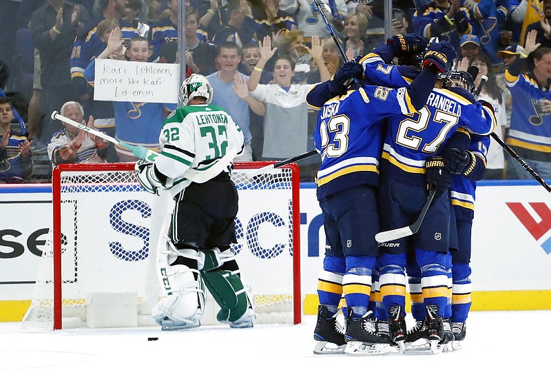 Teammates surround St. Louis Blues' Joel Edmundson after his goal past Dallas Stars goalie Kari Lehtonen, left, of Finland, during the first period of an NHL hockey game Saturday, Oct. 7, 2017, in St. Louis. 