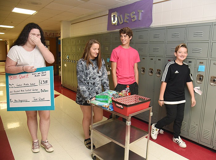 Elizabeth Jakob, left, laughs at a comment from Grayson Johnston, second from right, as they and fellow students Alli Rhoads, second from left, and Sebastian Neeley show one of the ways they raised money for Goodson Middle School relief. They went room to room selling candy, pencils and other items. They also are selling punch cards to Whaley's East End Drug for fountain sodas.