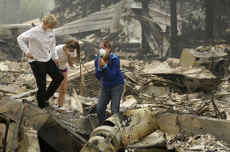 <p>AP</p><p>Mary Caughey, center in blue, reacts with her son Harrison, left, after finding her wedding ring Tuesday in debris at her home destroyed by fires in Kenwood, California.</p>