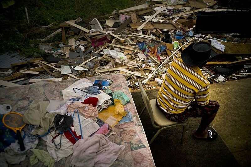 Efrain Diaz Figueroa spends the afternoon sitting on a chair next to the remains of the house of his sister destroyed by Hurricane Maria in San Juan, Puerto Rico, Monday, Oct. 9, 2017. Figueroa, who was visiting for a month at her sister Eneida's house when the Hurricane Maria hit the area, also lost her home in the Arroyo community. He waits for a relative to come from Boston and take him to Boston. He says that he is 70 years old and all his life working can't continue in these conditions in Puerto Rico. (AP Photo/Ramon Espinosa)