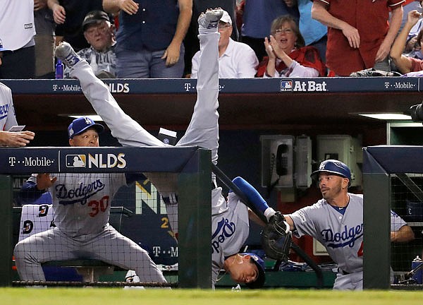 Dodgers first baseman Cody Bellinger falls in the dugout after catching a foul ball by the Diamondbacks' Jeff Mathis during the fifth inning Monday in Game 3 of the National League Division Series in Phoenix.