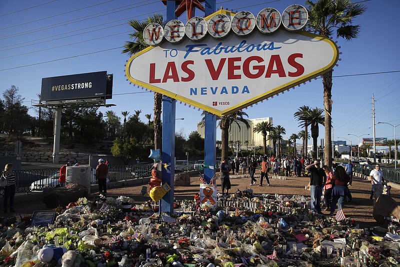 Flowers, candles and other items surround the famous Las Vegas sign at a makeshift memorial for victims of a mass shooting Monday, Oct. 9, 2017, in Las Vegas. Stephen Paddock opened fire on an outdoor country music concert killing dozens and injuring hundreds. (AP Photo/John Locher)