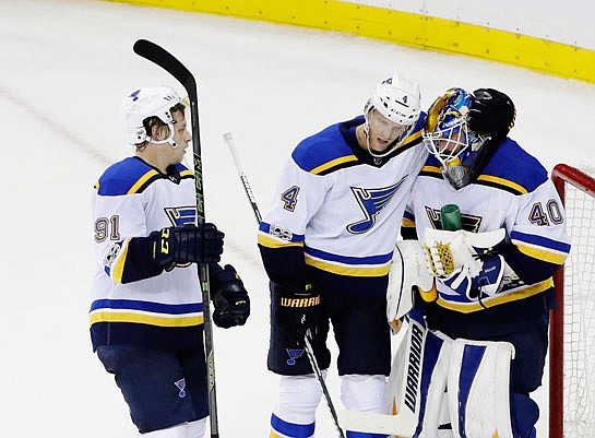 Blues goalie Carter Hutton celebrates with teammates Carl Gunnarsson (4) and Vladimir Tarasenko (91) after Monday night's 3-1 victory against the Rangers in New York.