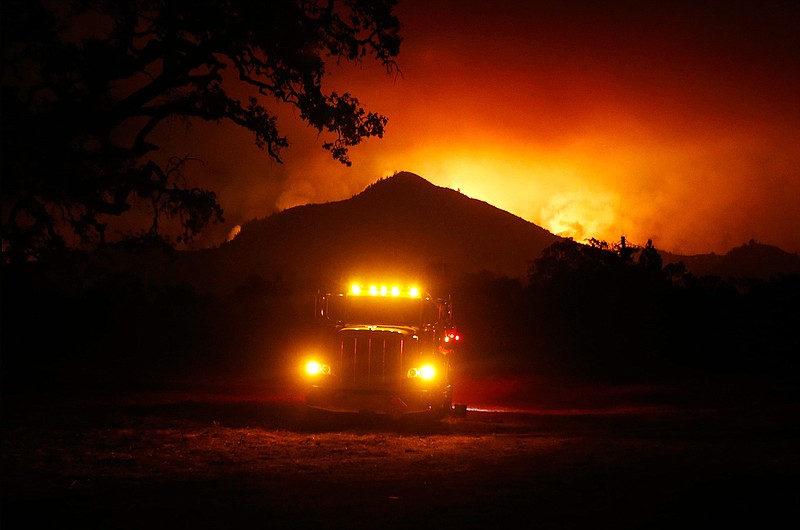 In this Tuesday, Oct. 10, 2017 photo, flames rise from a hillside east of Santa Rosa, Calif. Wildfires whipped by powerful winds swept through Northern California, sending residents on a headlong flight to safety through smoke and flames as homes burned. 