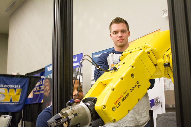 Evan Fitte, left, and Daniel Bryan, engineers with Cooper Tire, operate a robot arm, one of the displays at "Dream It, Do It," an orientation for eighth-graders from Texas Middle School to let them know about the possibilities of careers in industry.