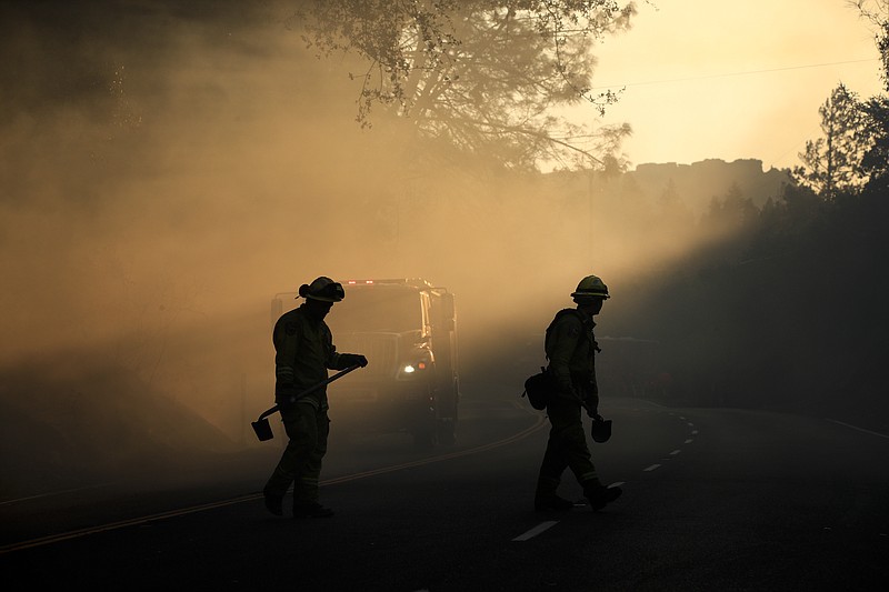 Two firefighters watch for spot fires Friday, Oct. 13, 2017, near Calistoga, Calif. Firefighters gained some ground on a blaze burning in the heart of California's wine country but face another tough day ahead with low humidity and high winds expected to return. (AP Photo/Jae C. Hong)