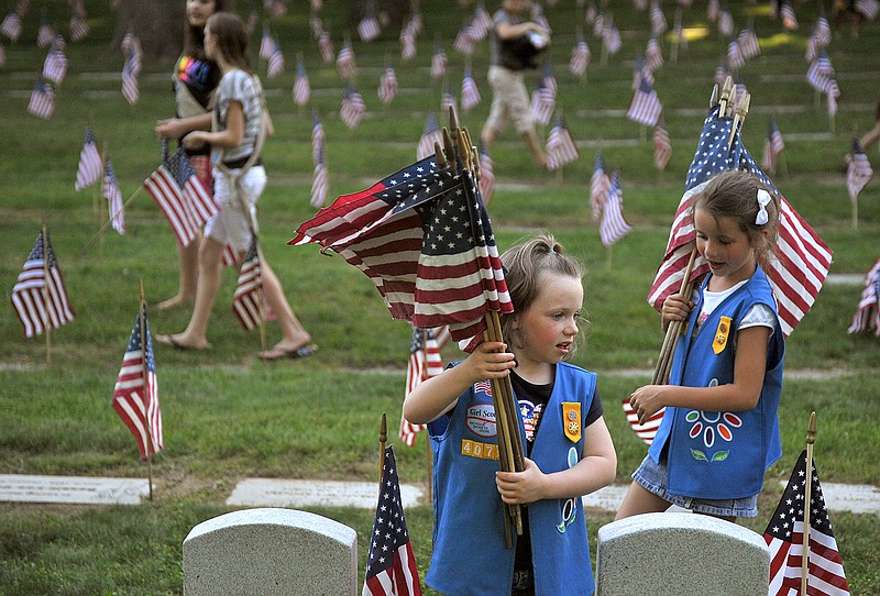In this May 23, 2012 file photo, Natalie Benson, 5, and Holly Sweezer, 6, carry extra flags as Boy and Girl Scouts place flags on each of the 5,000 headstones at the Grand Rapids Veterans State Cemetery in Grand Rapids, Mich. The Wednesday, Oct. 11, 2017 Boy Scouts of America announcement to admit girls throughout its ranks will transform what has been a mostly cordial relationship between the two iconic youth groups since the Girl Scouts of the USA was founded in 1912, two years after the Boy Scouts.