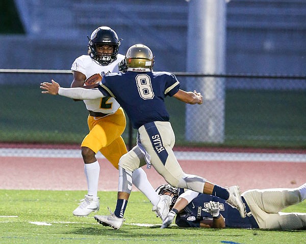 Helias teammates Daniel Rhea (8) and Jeremiah Heckman attempt to bring down Nate Peat of Rock Bridge during a game last month at Ray Hentges Stadium.