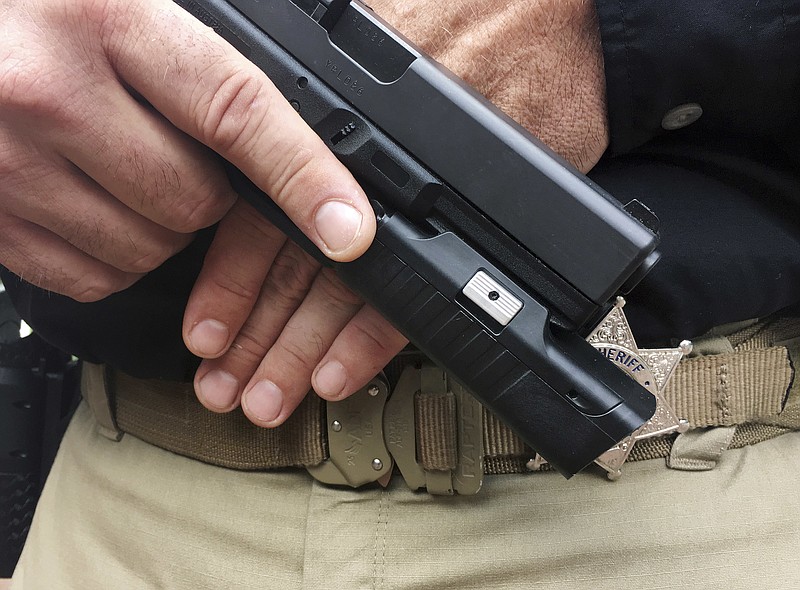 In this Sept. 23, 2017 photo provided by Centinel Solutions, a model displays a camera mounted below the barrel of a handgun in New York. Some police departments are considering putting cameras on officers' guns, saying they would give a better, unobstructed view of police-involved shootings and save money on video storage costs compared with body cameras. (Gavin Smith/Centinel Solutions via AP)