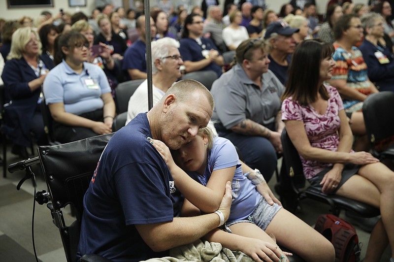 Las Vegas shooting victim Kurt Fowler embraces his 10-year-old daughter Timori Fowler during a country music performance at Sunrise Hospital, Wednesday, Oct. 11, 2017, in Las Vegas. Kurt Fowler was shot in the mass shooting at a music festival in Las Vegas.(AP Photo/John Locher)