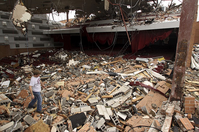 FILE - in this May 24, 2011, file photo, Joplin High School sophomore Landan Taylor makes has way across the wreckage of the school's theater after the school was heavily damaged by a tornado in Joplin, Mo. More than six years after the massive tornado tore through Joplin, the local school district has rebuilt its facilities and filled them with thousands of students. But it's still haggling with the Federal Emergency Management Agency amount how much money it's due. (AP Photo/Mark Schiefelbein, File)