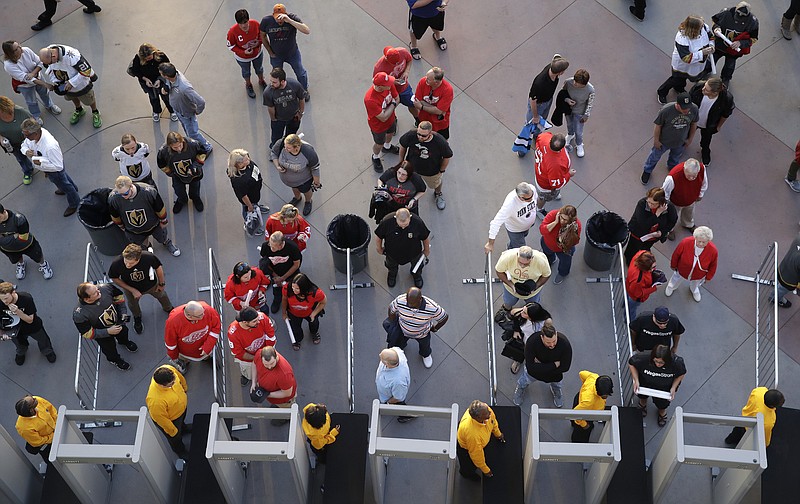 In this Oct. 13, 2017, photo, people wait to go through security at the T-Mobile arena before an NHL hockey game in Las Vegas. The Las Vegas tourism sector is bracing for changes in the aftermath of the massacre that killed 58 people at an outdoor music festival. (AP Photo/John Locher)