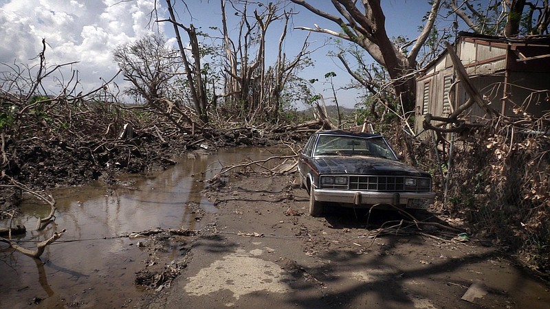 Mud puddles of water and a washed out car litter the front of Hernan Cabrera's house in the Media Luna neighborhood of Toa Baja, Puerto Rico, on October 12, 2017. 