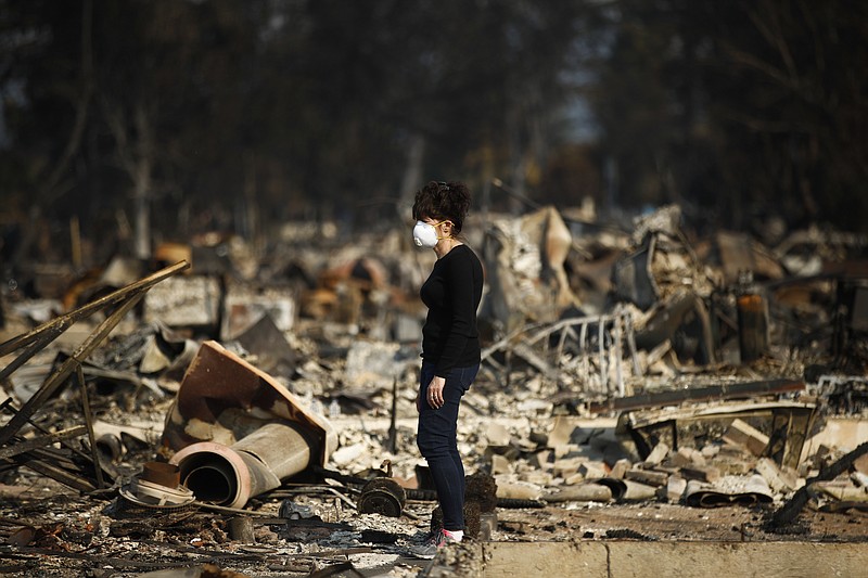 Karen Curzon stands in what remains of her home, which was destroyed by a wildfire in the Coffey Park neighborhood, Sunday, Oct. 15, 2017, in Santa Rosa, Calif. "We are going to rebound, rebuild and get this community back," said Curzon. (AP Photo/Jae C. Hong)