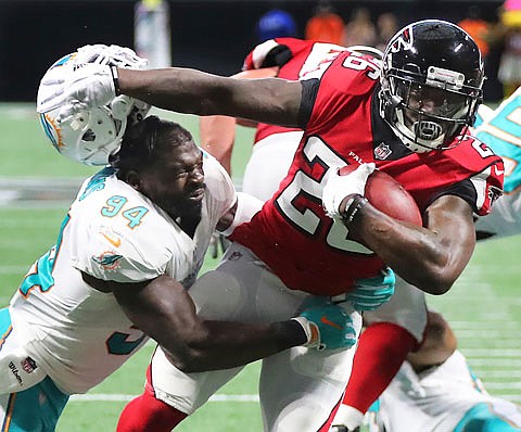 Falcons running back Tevin Coleman separates Dolphins linebacker Lawrence Timmons from his helmet as he breaks the tackle to run for a touchdown during the second half of Sunday's game in Atlanta.