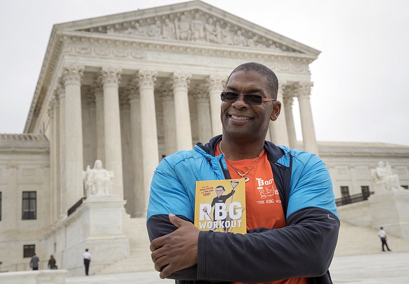 In this Oct. 13, 2017, photo, Bryant Johnson, personal trainer for Supreme Court Justice Ruth Bader Ginsburg poses in Washington, with his new book, "The RBG Workout: How She Stays Strong ... and You Can Too!" Besides the 84-year-old Ginsberg, Johnson, who now also trains Justice Stephen Breyer and Justice Elena Kagan. Johnson says he hopes the book will help convince people: “You’re never too old to do something.”  (AP Photo/J. Scott Applewhite)