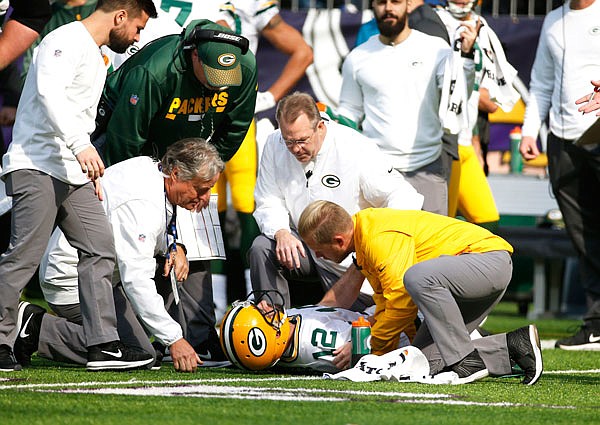 Packers quarterback Aaron Rodgers (12) is attended to by medical staff after being hit by Vikings outside linebacker Anthony Barr in the first half of Sunday's game in Minneapolis.