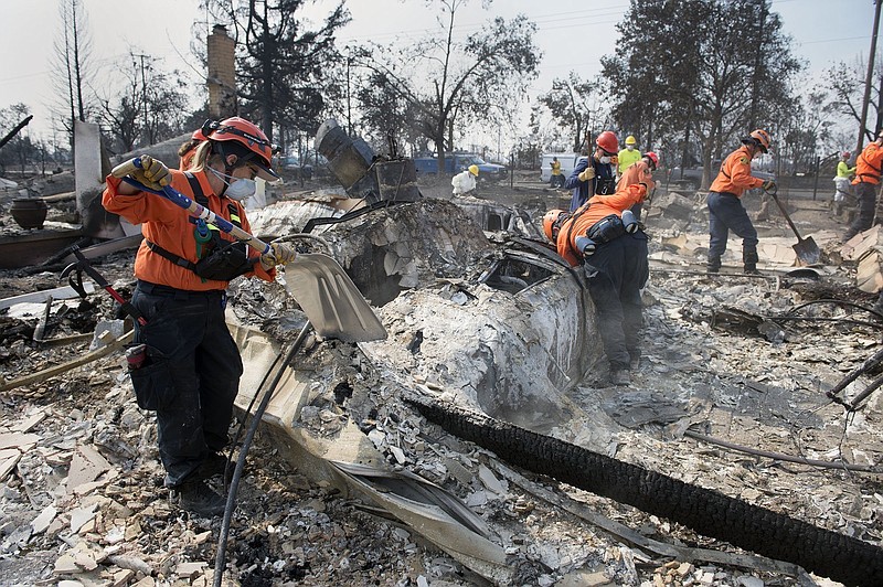 Search and rescue members from Alameda and Marin counties search Monday, Oct. 16, 2017, inside a car that is covered in debris in Coffey Park in Santa Rosa, Calif.