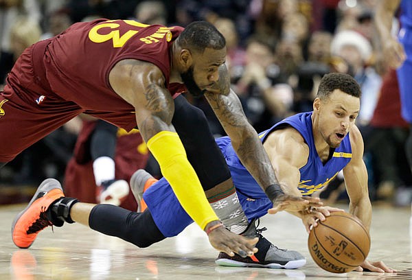 This Sunday, Dec. 25, 2016, file photo shows LeBron James of the Cavaliers and Stephen Curry of the Warriors battling for a loose ball during a game in Cleveland. 