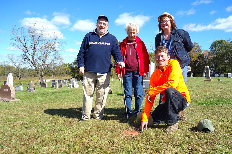 Austin Toebben, kneeling, grave mapper Michael Banak, left, and Middle River Cemetery Association members Lola Wekenborg and Faye Zumwalt gather around one of the new brick markers Toebben placed at unmarked and unidentified Middle River Cemetery graves.
