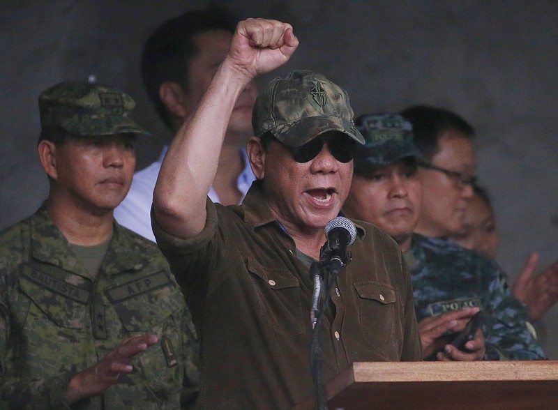 President Rodrigo Duterte cheers Tuesday, Oct. 17, 2017, as he declares the liberation of Marawi city in southern Philippines after almost five months of the siege by pro-Islamic State group militants. Gunfire rang out sporadically and explosions thudded as Philippine soldiers fought Tuesday to gain control of the last pocket of Marawi controlled by Islamic militants as President Duterte declared the southern city liberated from "terrorist influence."